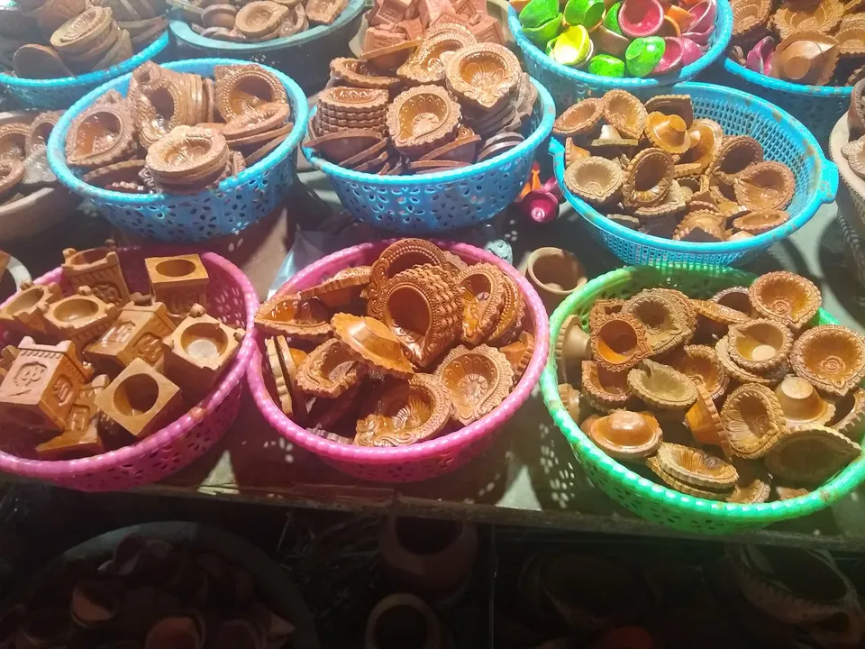 Clay diyas laid out for sale in colourful plastic baskets
