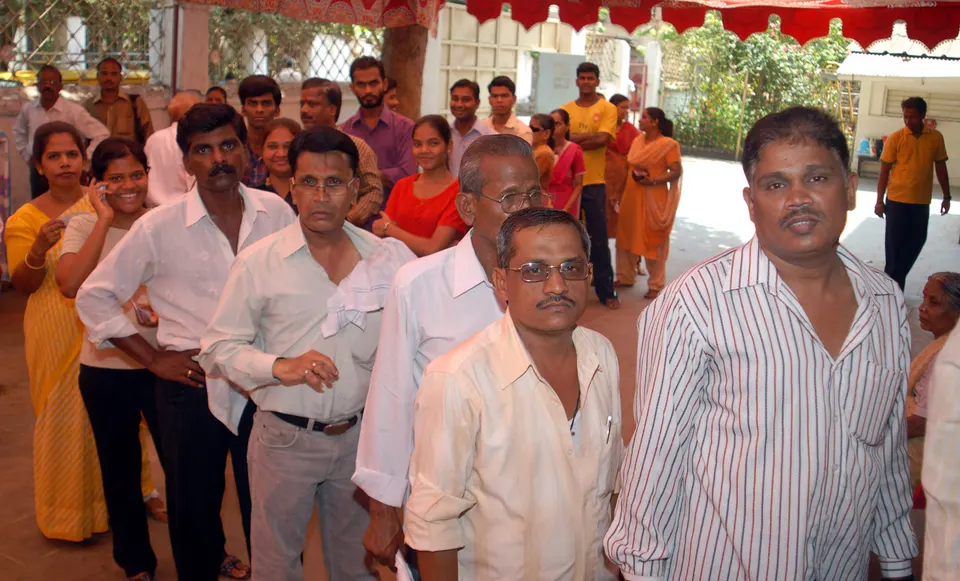 Men and women voters standing in a queue in the courtyard outside a polling station