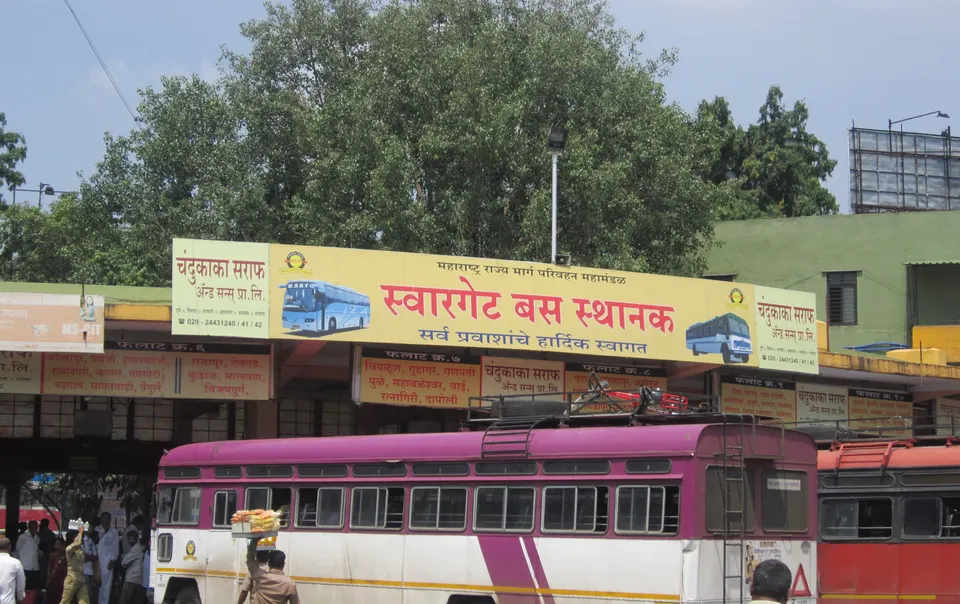 An MSRTC bus and passengers beneath the sign at Swargate bus station in Pune