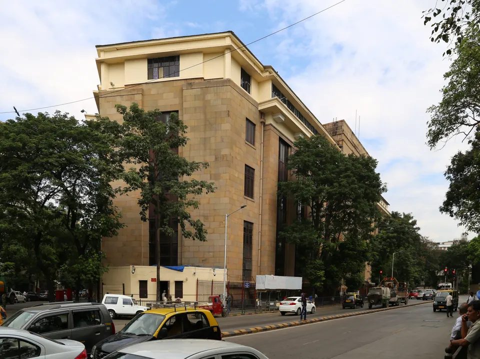 झाडांनी वेढलेली मुंबईतील भारतीय रिझर्व्ह बँकेची दगडी इमारत आणि समोरचा रस्ता